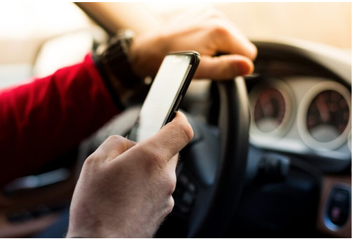 Hand holding mobile phone while driving