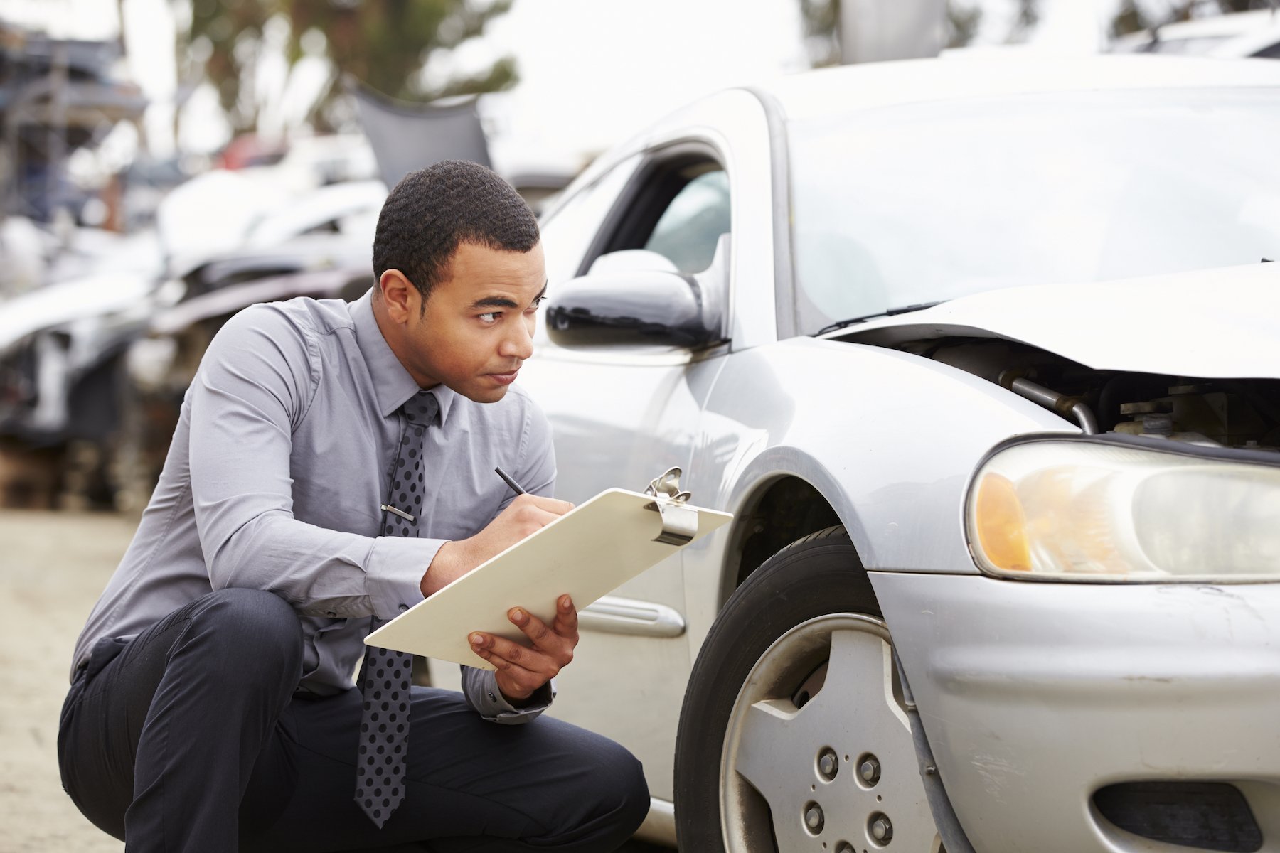 Insurance adjuster inspecting a car following a fender bender