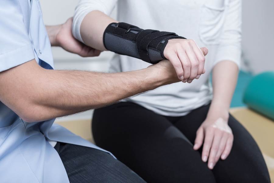 Physical therapist helping woman with broken arm following a construction site injury