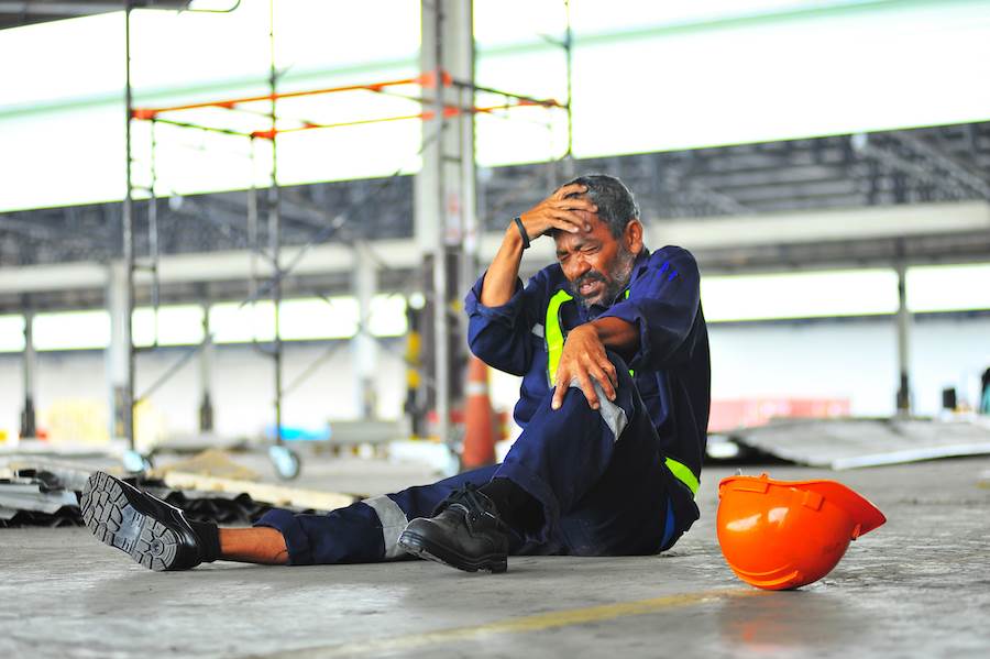 Construction worker on ground after an accident, and his hard hat has fallen off