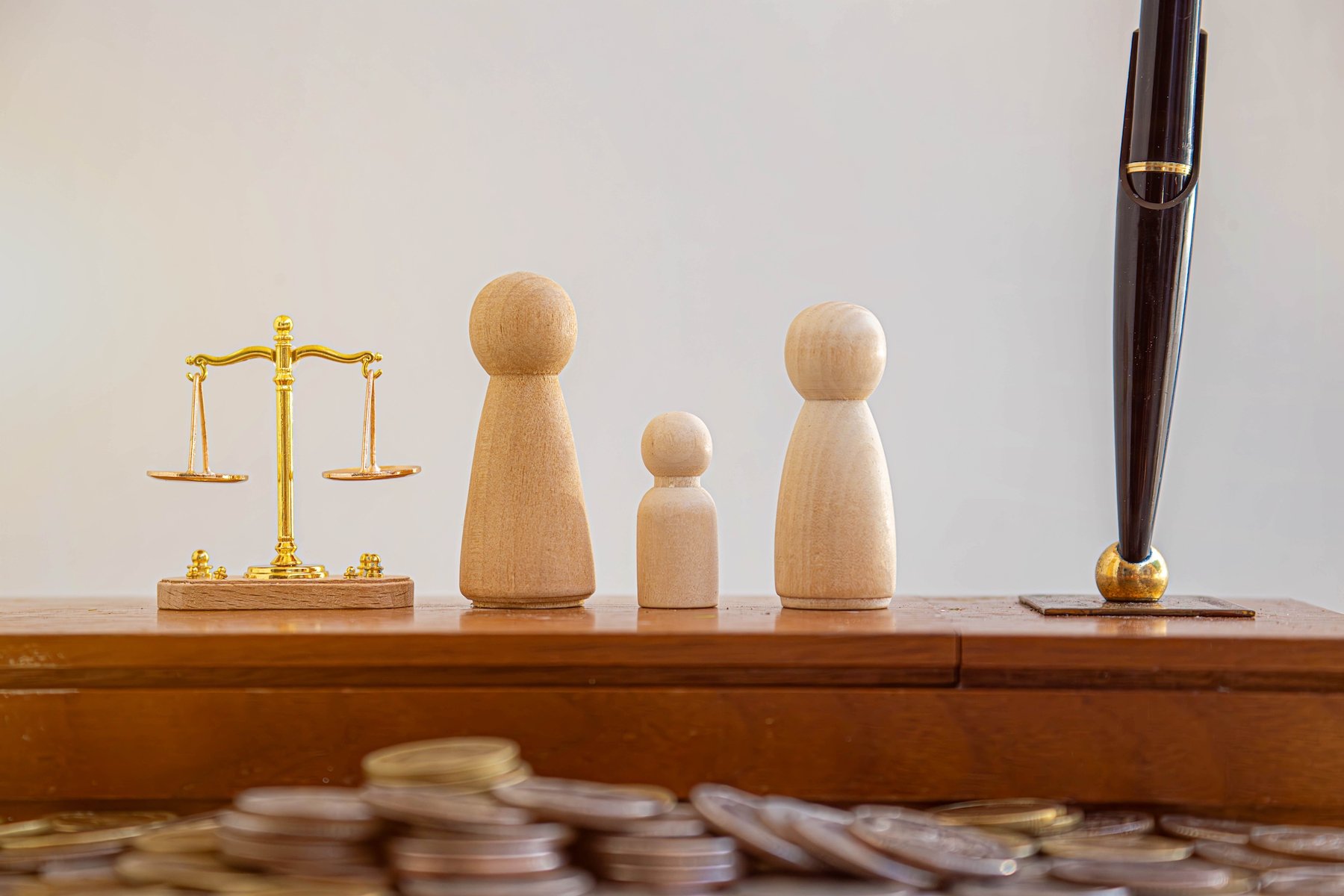 scale of justice next to wooden representations of a child and guardians
