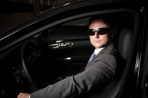 driver in sunglasses and suit in dark vehicle