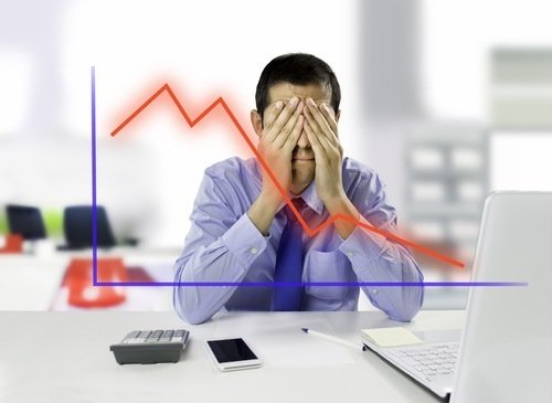Business owner at work desk with hand covering eyes in apparent frustration