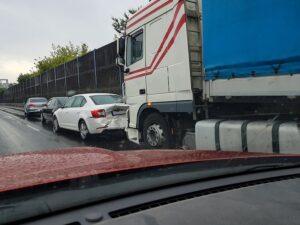 Aftermath of a white semi truck rear-ending a white sedan on a cloudy day