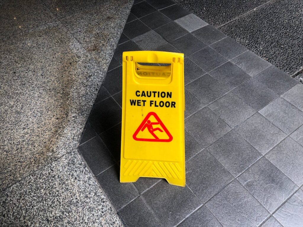 Yellow and red caution wet floor sign on a tile floor