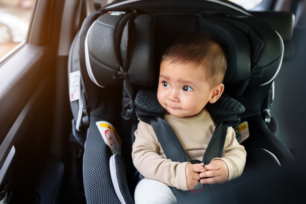happy infant baby sitting in car seat and looking out of the window